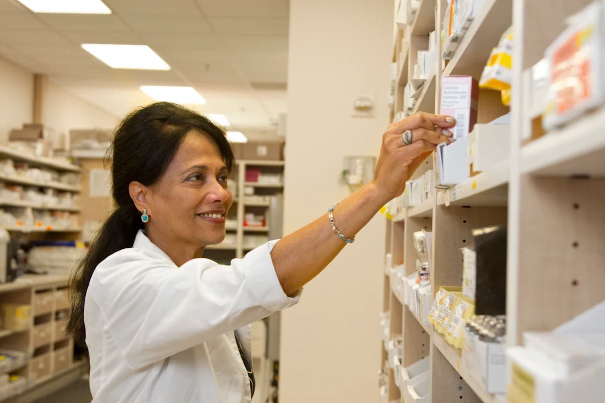 A pharmacist taking a medicine from the dispensary shelf